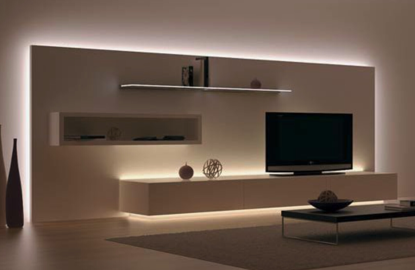 Moderne Wohnzimmerwand mit Flachbild-TV, schwebendem Regal und LED-Beleuchtung.