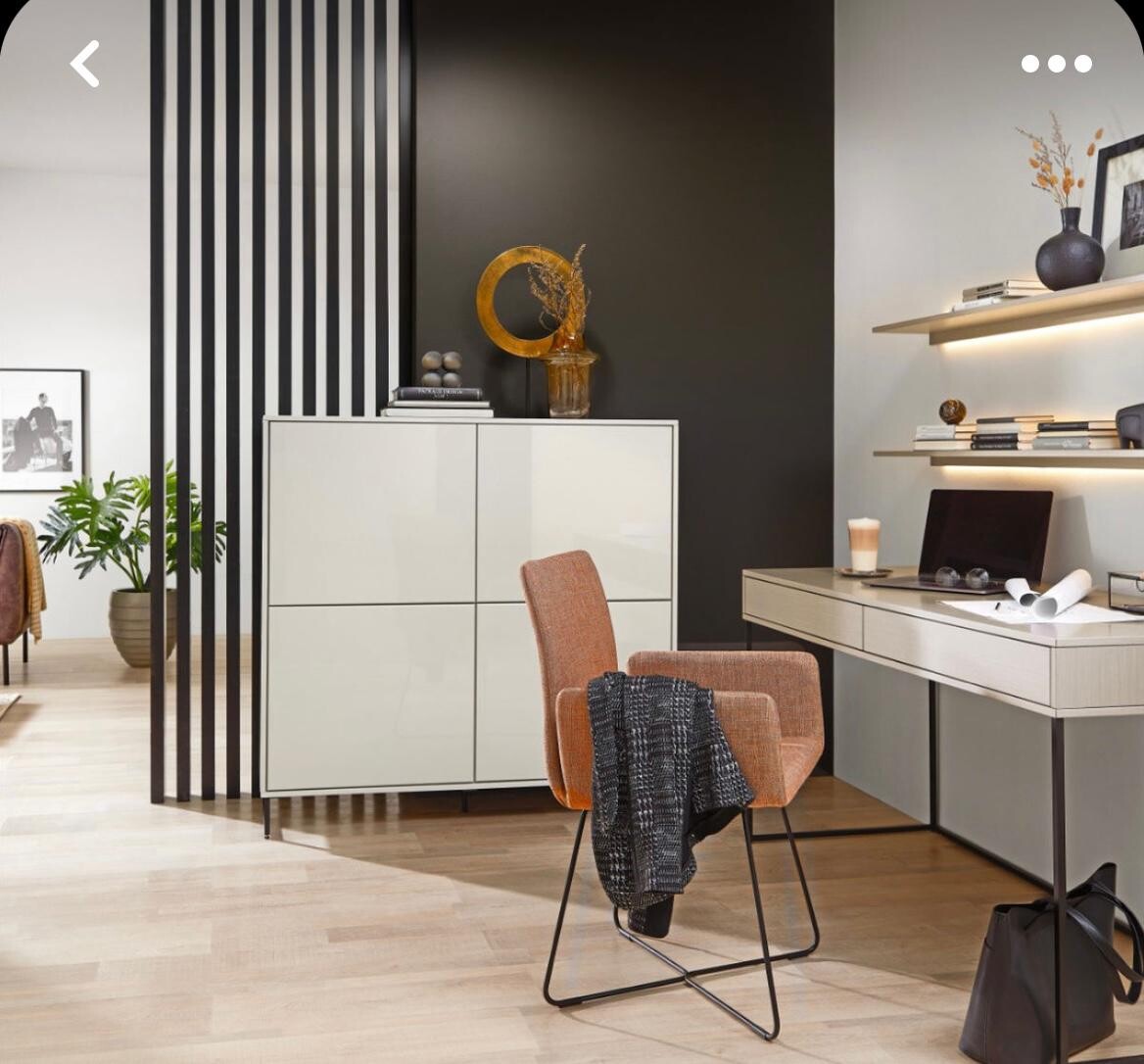 Modernes Arbeitszimmer/Wohnzimmer: heller Schreibtisch, orange Stuhl, Regal, Pflanzen, dunkle Wand.