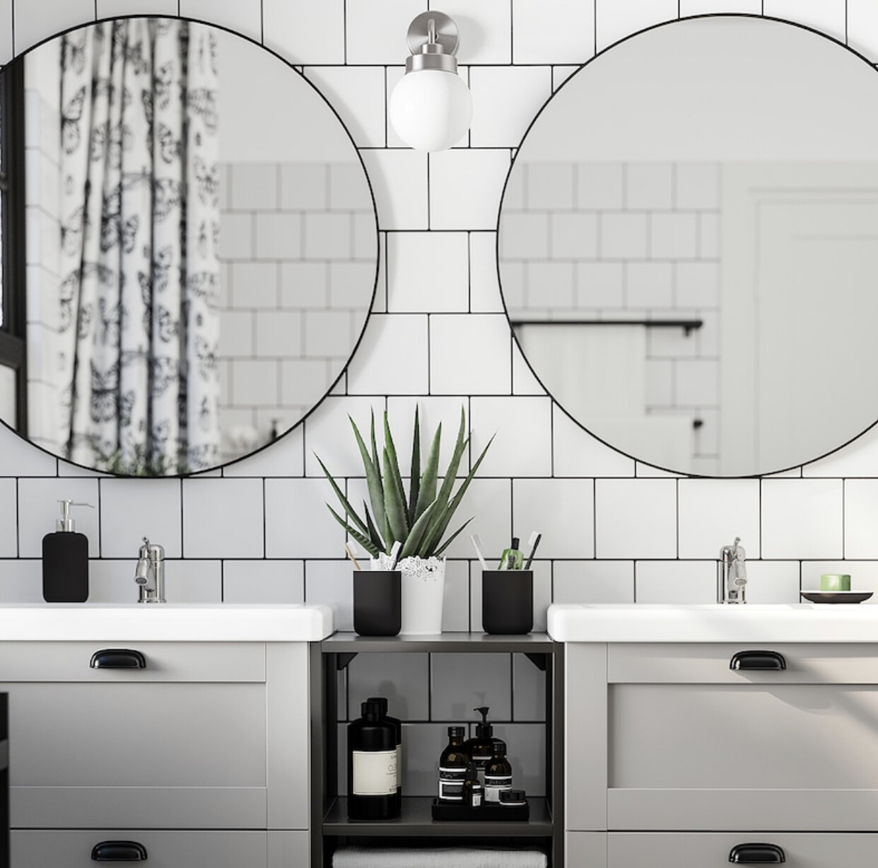 Doppelwaschtisch mit zwei runden Spiegeln, weiße Fliesenwand, Aloe-Pflanze und Badzubehör.