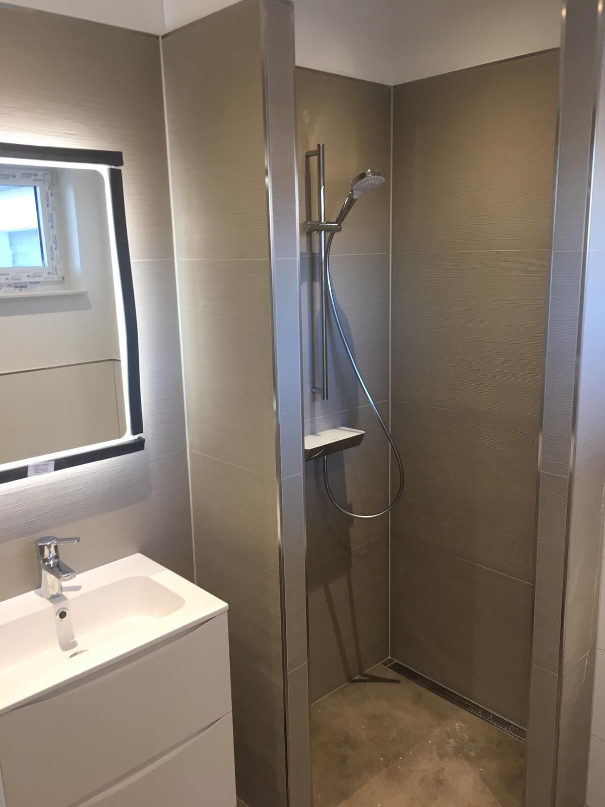 Modernes Badezimmer mit Dusche (Metallrahmen), Handbrause, Wandfliesen, Waschbecken und Spiegel.