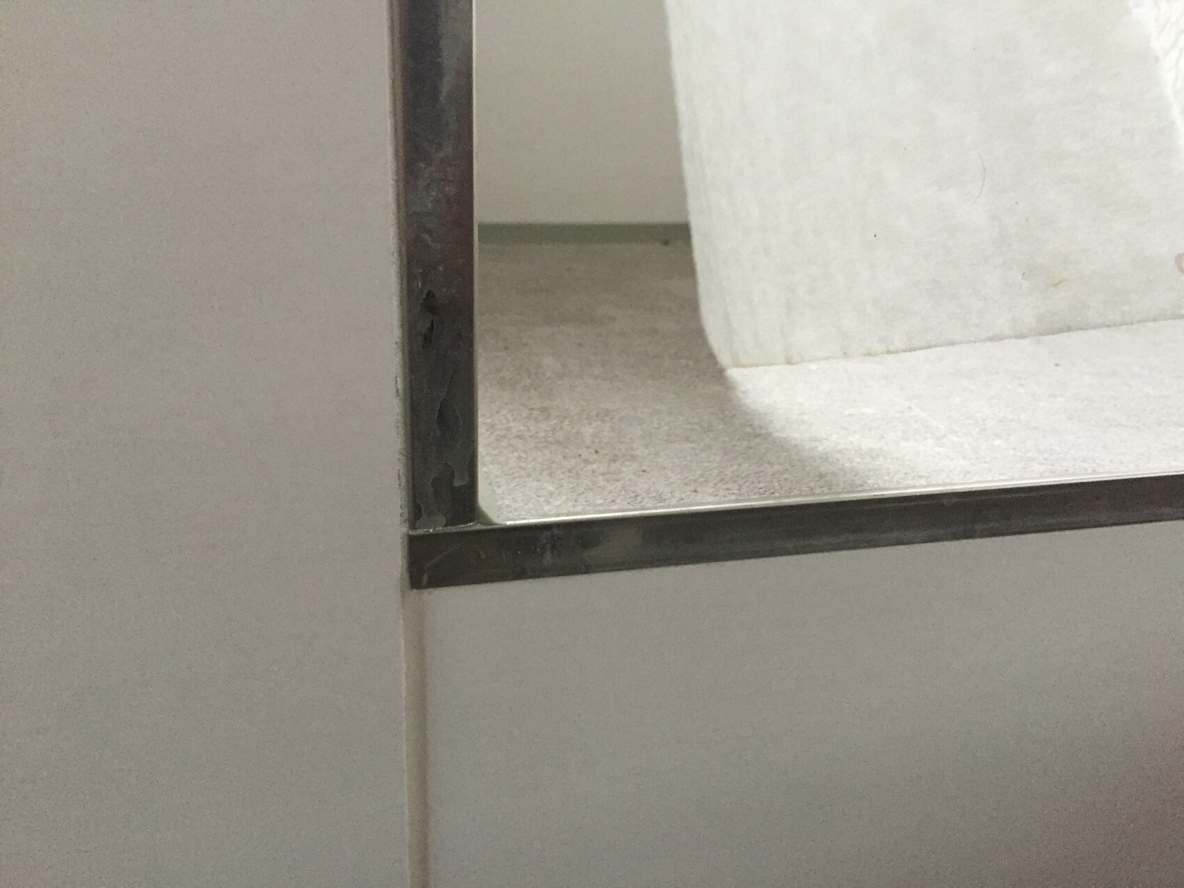Nahaufnahme eines Badezimmerspiegels mit Metallrahmen an Fliesenwand