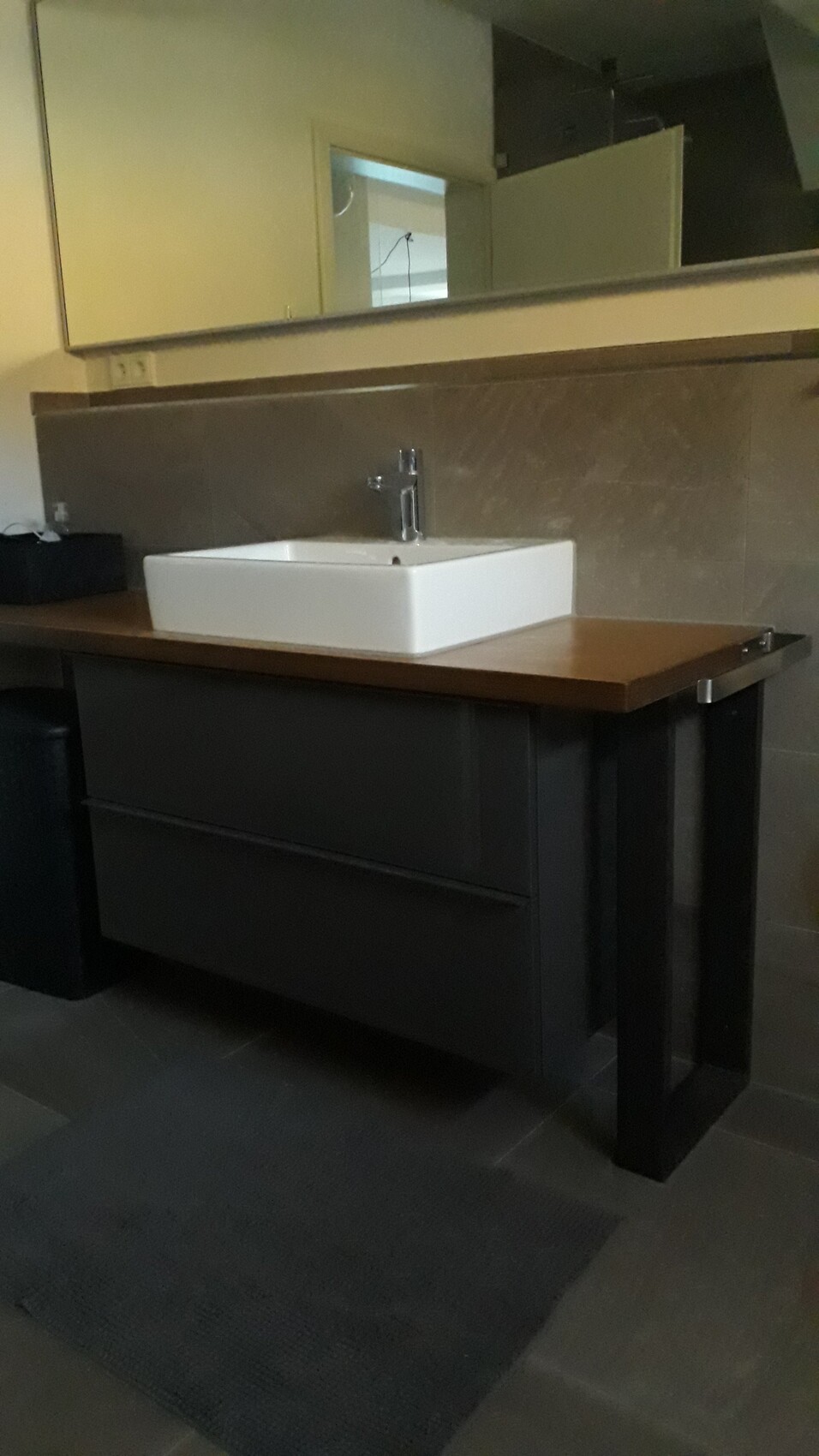 Moderner Badezimmer-Waschtisch mit weißer Spüle, Holzplatte und dunklem Unterschrank.