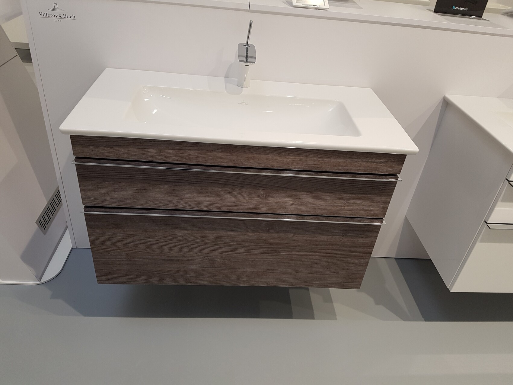 Waschtisch mit weißer Spüle und dunklem Holz-Unterschrank mit drei Schubladen.