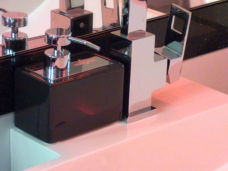 Moderne Chrom-Armatur mit schwarzem Seifenspender am Waschbecken, Spiegel im Hintergrund