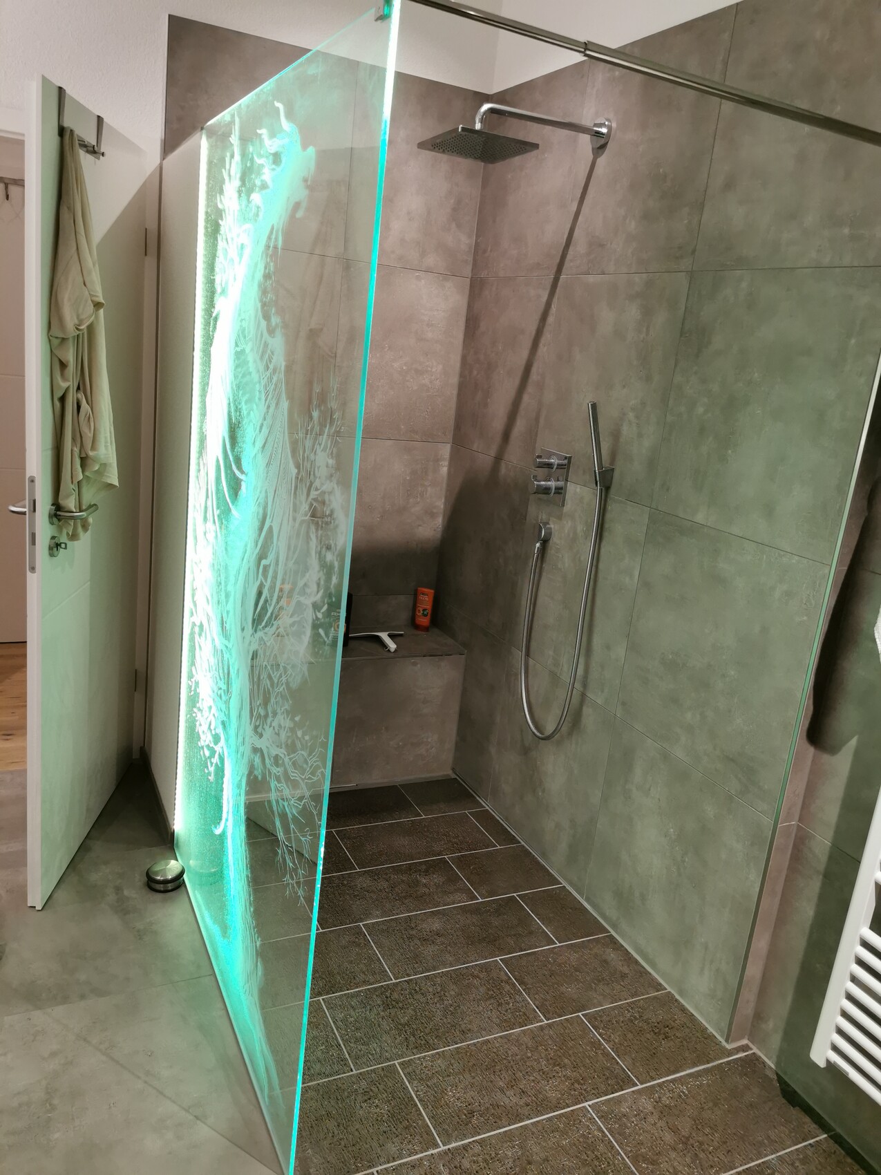 Moderne Dusche mit Glaswand, Regendusche, Handbrause, grauen Wandfliesen und braunen Bodenfliesen.