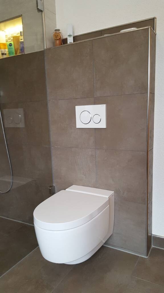 Modernes Badezimmer mit wandhängender Toilette, grauen Fliesen und Dusche