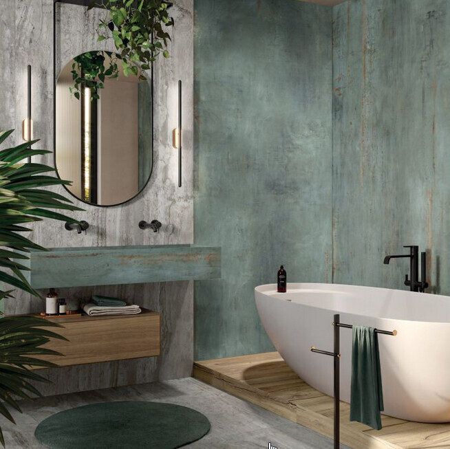 Modernes Badezimmer mit freistehender weißer Badewanne, Spiegel, Holzboden, grüne Wände und Pflanzen.