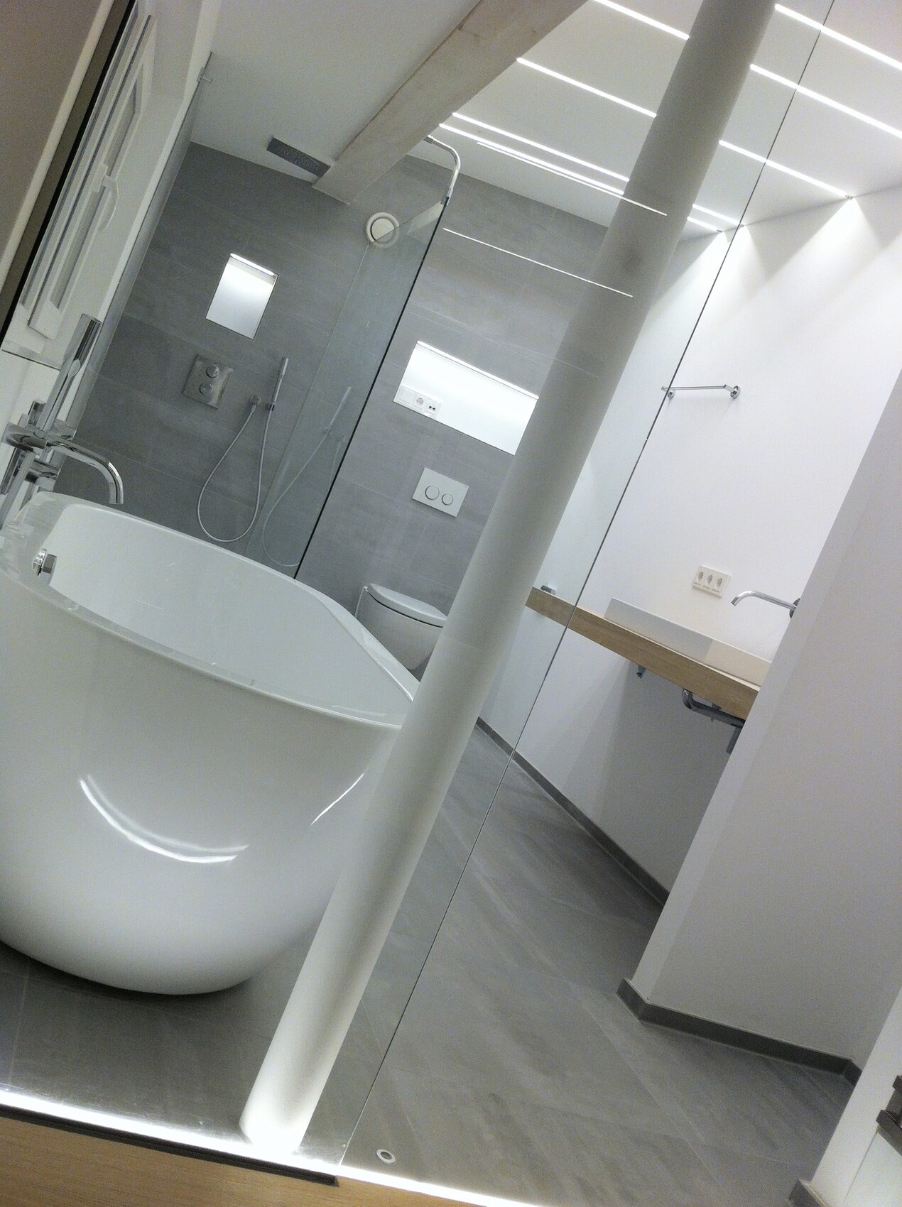 Modernes Badezimmer mit freistehender Badewanne, Glasabtrennung und Toilette.