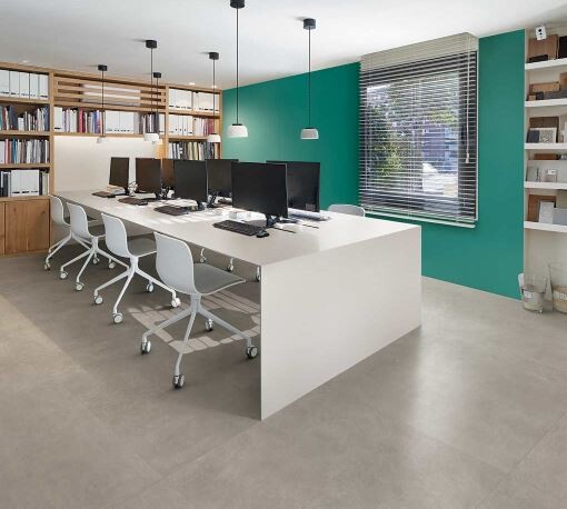 Moderner Büroraum mit langem weißen Tisch, Monitoren, weißen Stühlen, Bücherregalen und grüner Wand.