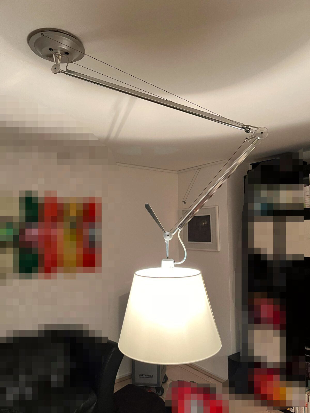 Kreisförmige Deckenhalterung mit langem, verstellbarem Metallarm und hängendem Lampenschirm im Raum.