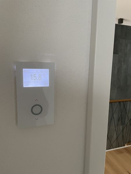 Wandthermostat mit digitalem Display zeigt 15.8°C und Bedienelemente.