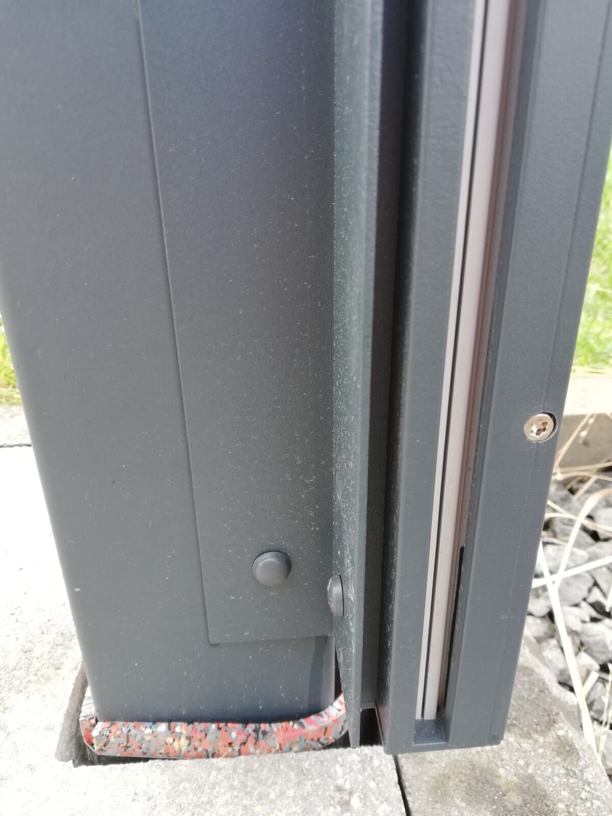 Nahaufnahme eines grauen Metallrahmens mit Dichtung, Schraubenkopf sichtbar.