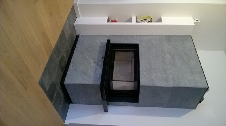 Moderner eingebauter Kaminofen aus grauem Stein mit Glasfront und Holzfußboden