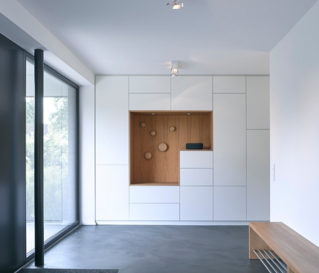 Moderne weiße Einbauwand mit Holznische und runden Holzelementen, minimalistischer Raum