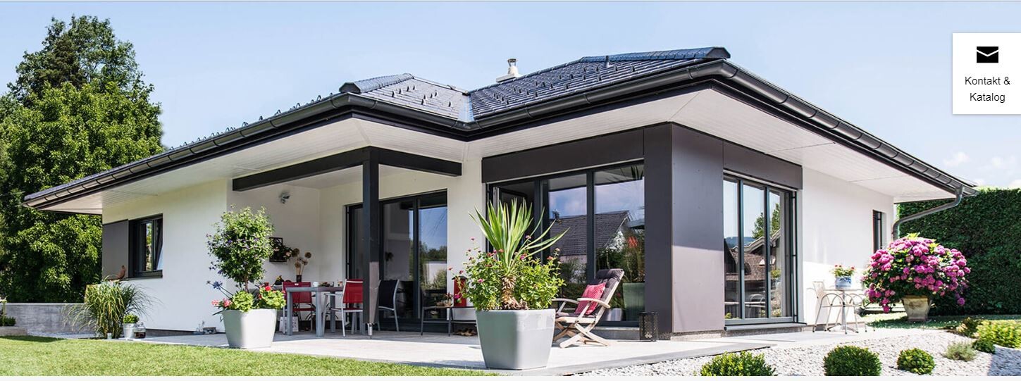 Modernes Einfamilienhaus mit großen Glasfronten, Terrasse und Gartenpflanzen.