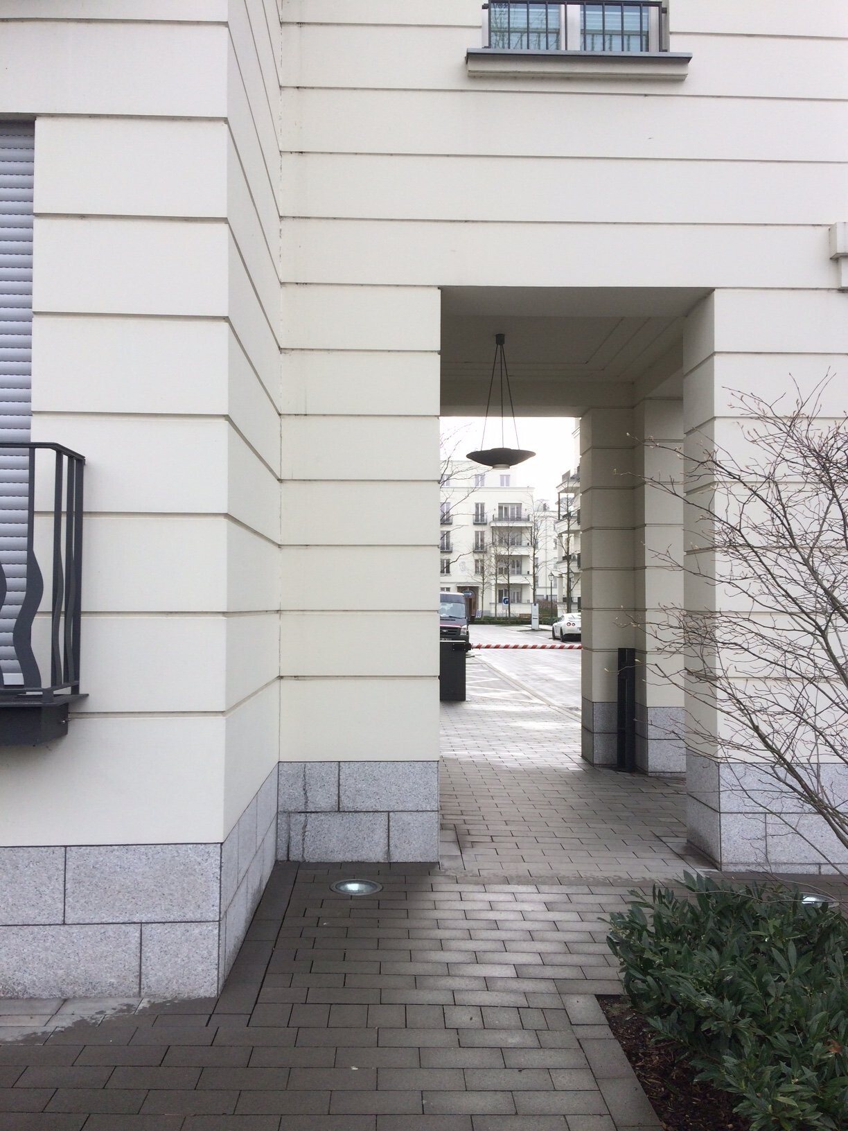 Heller Gebäudeeingang mit Durchgangspassage, Pflasterweg, städtische Umgebung.