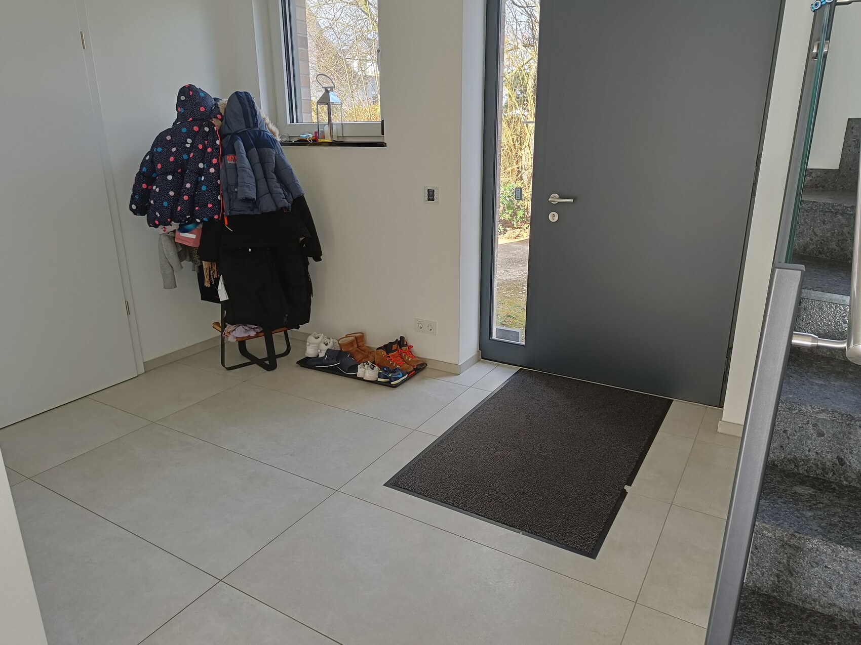 Flur/Eingangsbereich: Garderobe mit Jacken, Schuhe, Fußmatte vor Tür.