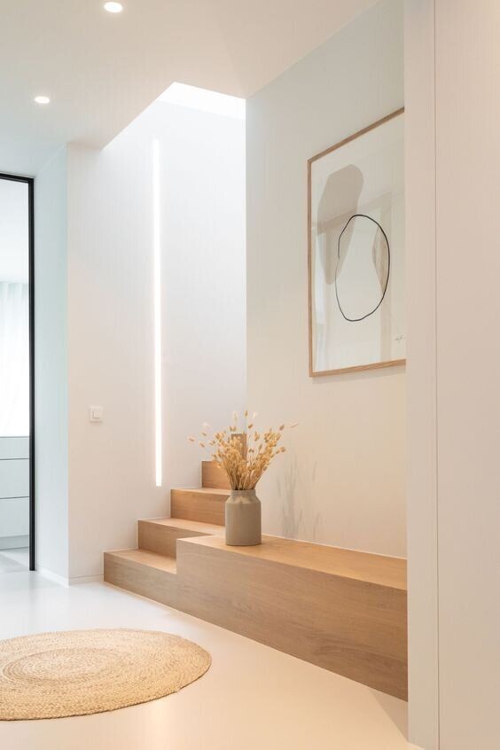Moderner Eingangsbereich mit Holzstufen, Vase mit Trockenblumen, LED-Lichtstreifen und Wandbild.