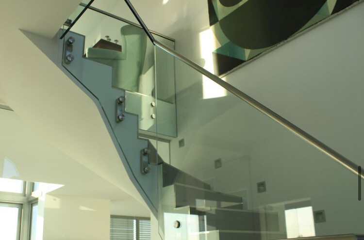 Moderne Glas-Treppenstufen mit Edelstahl-Handlauf in einem hellen Innenraum.