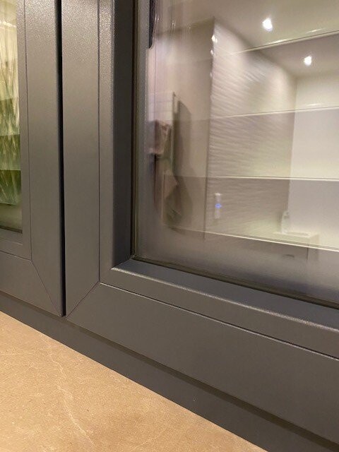 Metallrahmenfenster; Blick in ein weiß gefliestes Badezimmer.