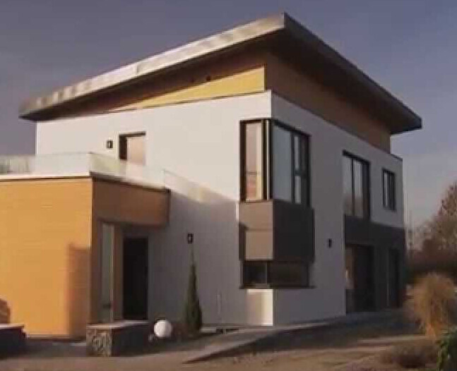 Modernes zweistöckiges Haus mit Flachdach, weißer Fassade, gelben Akzenten und großen Fenstern.