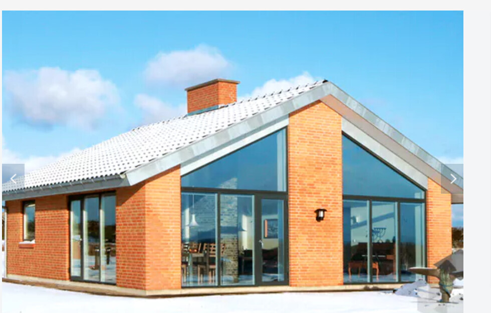 Modernes Einfamilienhaus aus roten Ziegeln mit großen Glasfronten und Winterlandschaft.