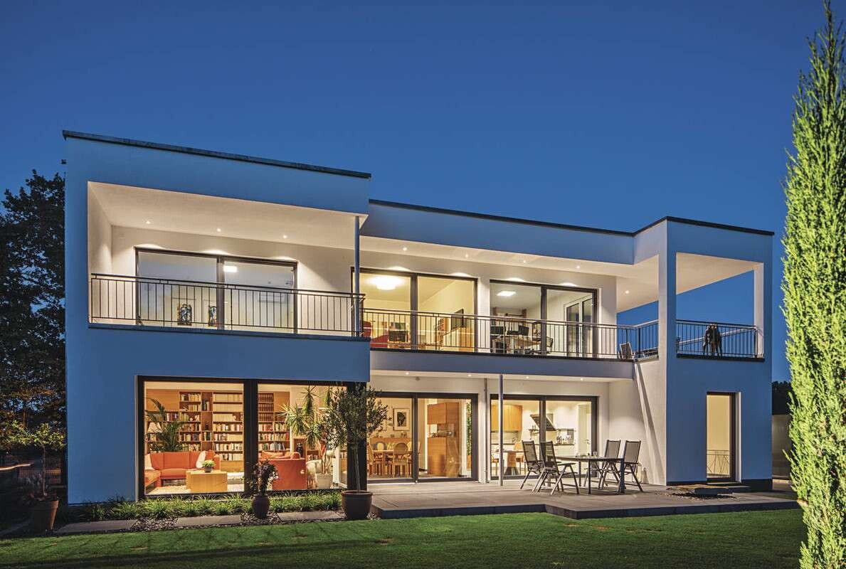 Moderne zweistöckige Villa mit Glasfront, Balkon und Terrasse bei Nacht