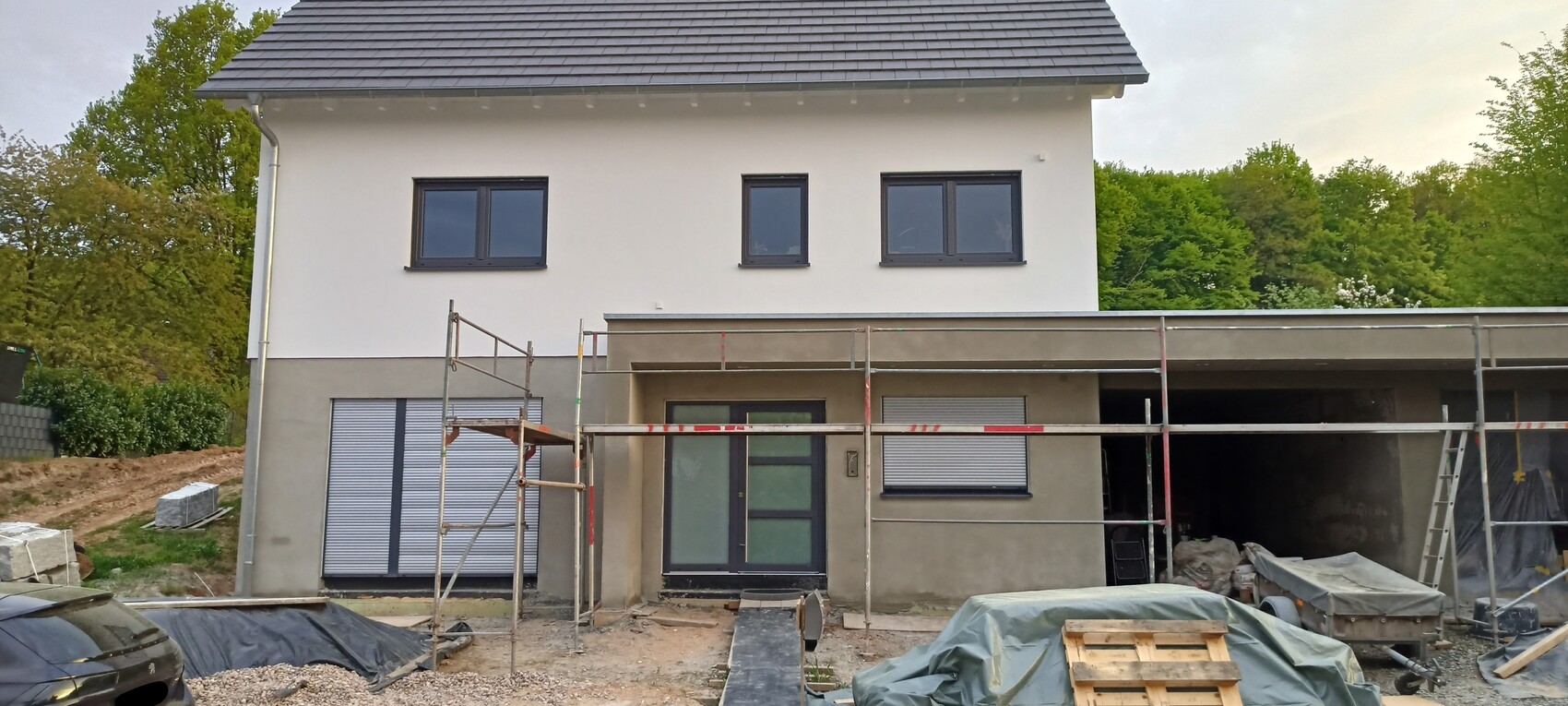 Neubau: Zweigeschossiges Wohnhaus im Bau mit Gerüst und Baustoffen vor dem Eingang.