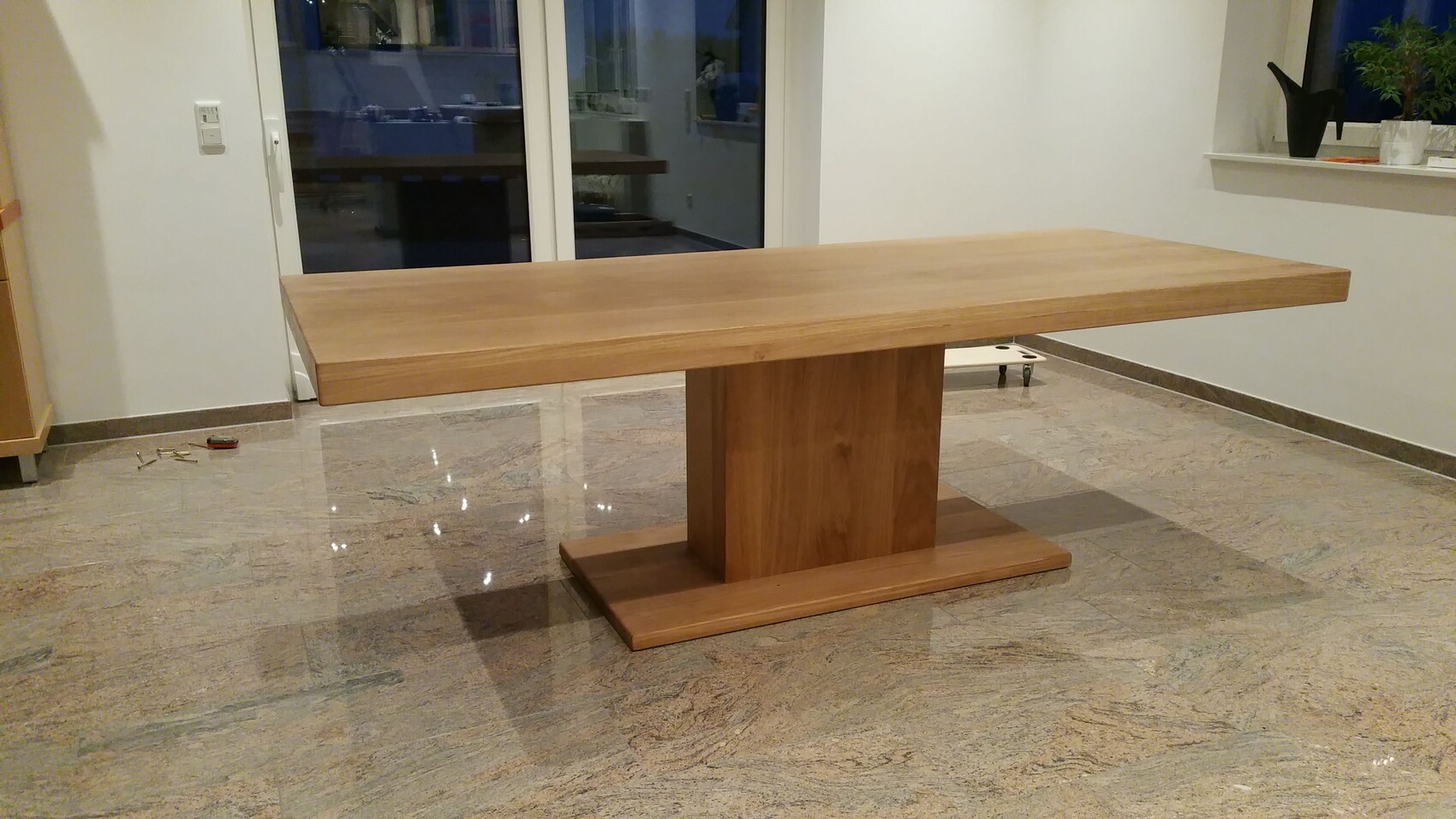 Breiter Holztisch mit zentraler Blocksäule in hellem Innenraum.