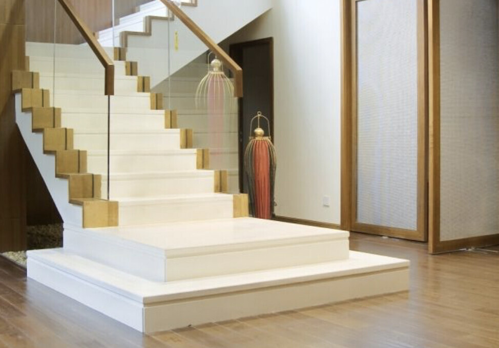 Moderne Innenaufnahme: weiße Treppe mit Glasgeländer, Holzboden und dekorative Lampen im Hintergrund.