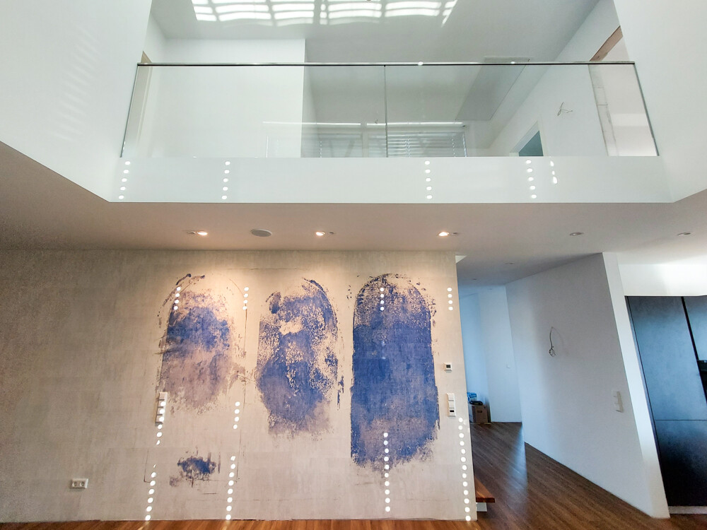 Moderner Innenraum mit Glasgeländer, Holzboden und dreifacher blauer Wandkunst.