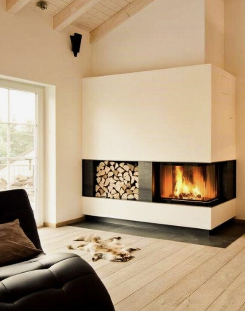 Wohnzimmer mit Kamin, Holzvorrat daneben, heller warmer Raum
