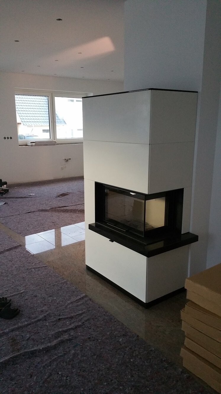 Moderner freistehender Kaminofen in weißem Gehäuse mit Glasfront in hellem unfertigem Wohnraum