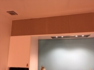 Moderner Küchenbereich mit blauer Wand hinter Holz-Fronten und integriertem Dunstabzug