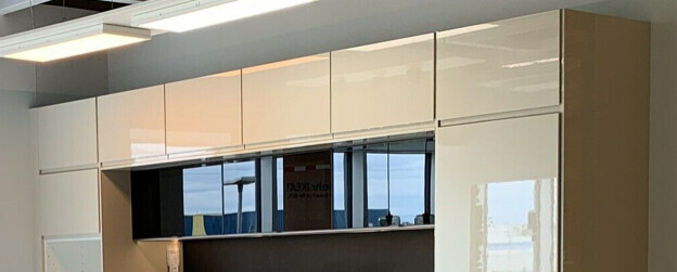 Moderne weiße Hochglanz-Schrankwand im Büro mit einem schwarzen offenen Fach.