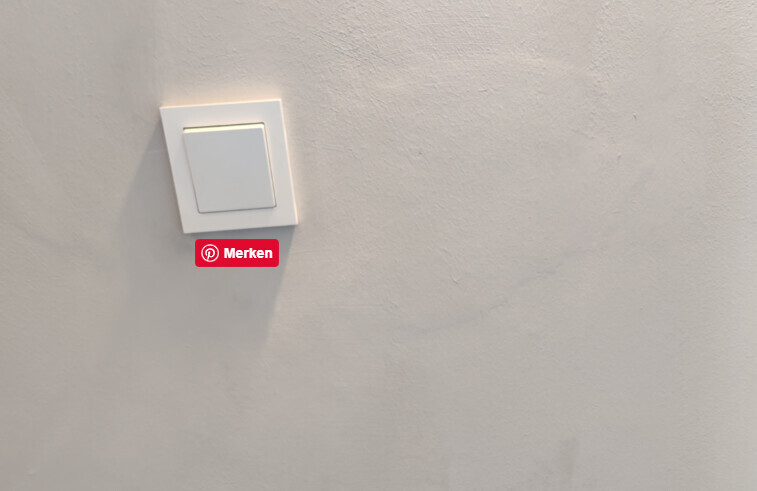 Weißer Wandschalter an grauer Wand, darunter rotes Merken-Label (Pinterest).