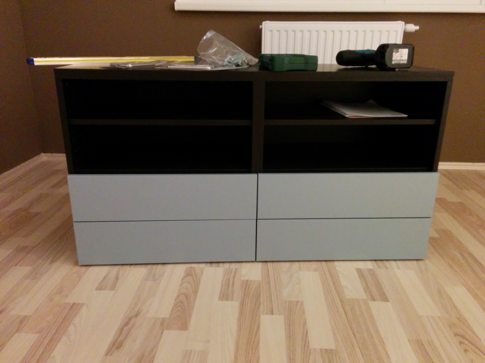 Moderne Sideboard: obere schwarze Fächer, darunter graue Schubladen; Werkzeuge darauf.
