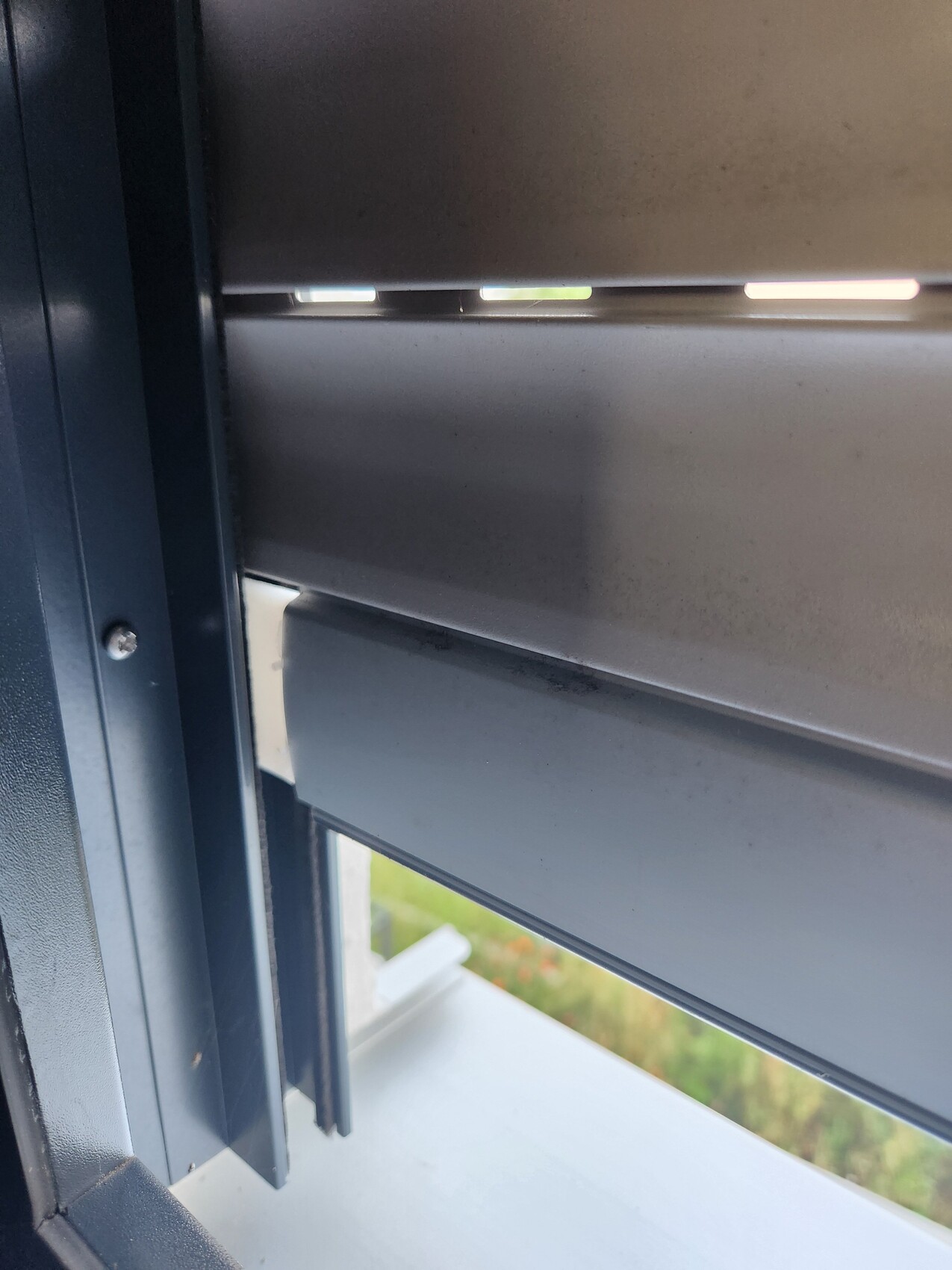 Nahaufnahme einer horizontalen Fensterjalousie mit geöffneten Lamellen; Lichtstrahlen durch Spalten.
