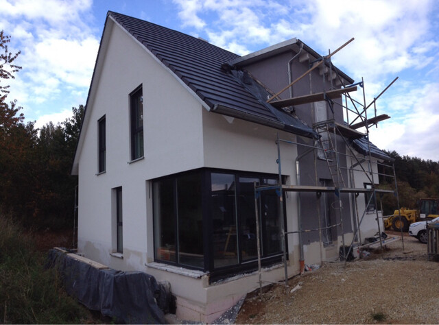 Modernes zweistöckiges Haus im Bau mit Gerüst und großen Glasfronten