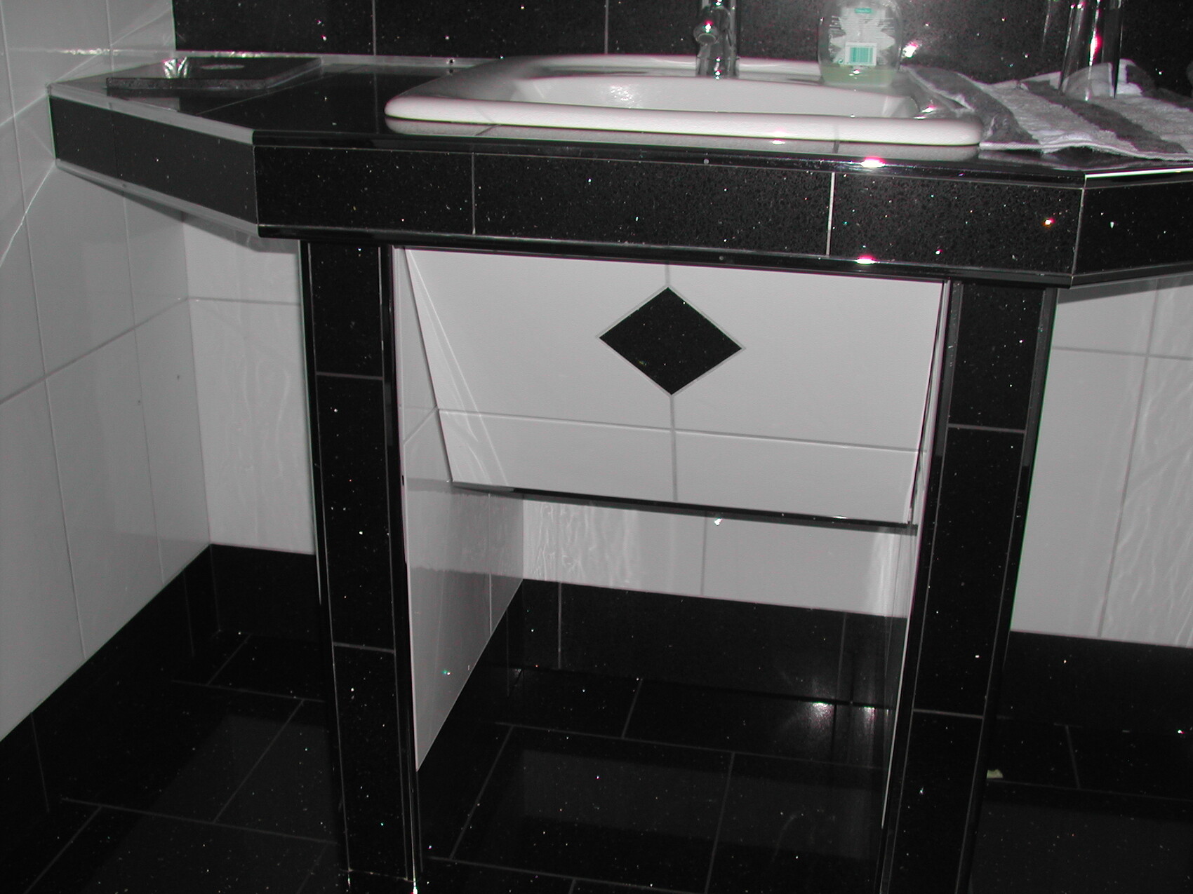 Modernes Badezimmer-Waschtisch mit schwarzem Granitrand und weißem Unterschrank.