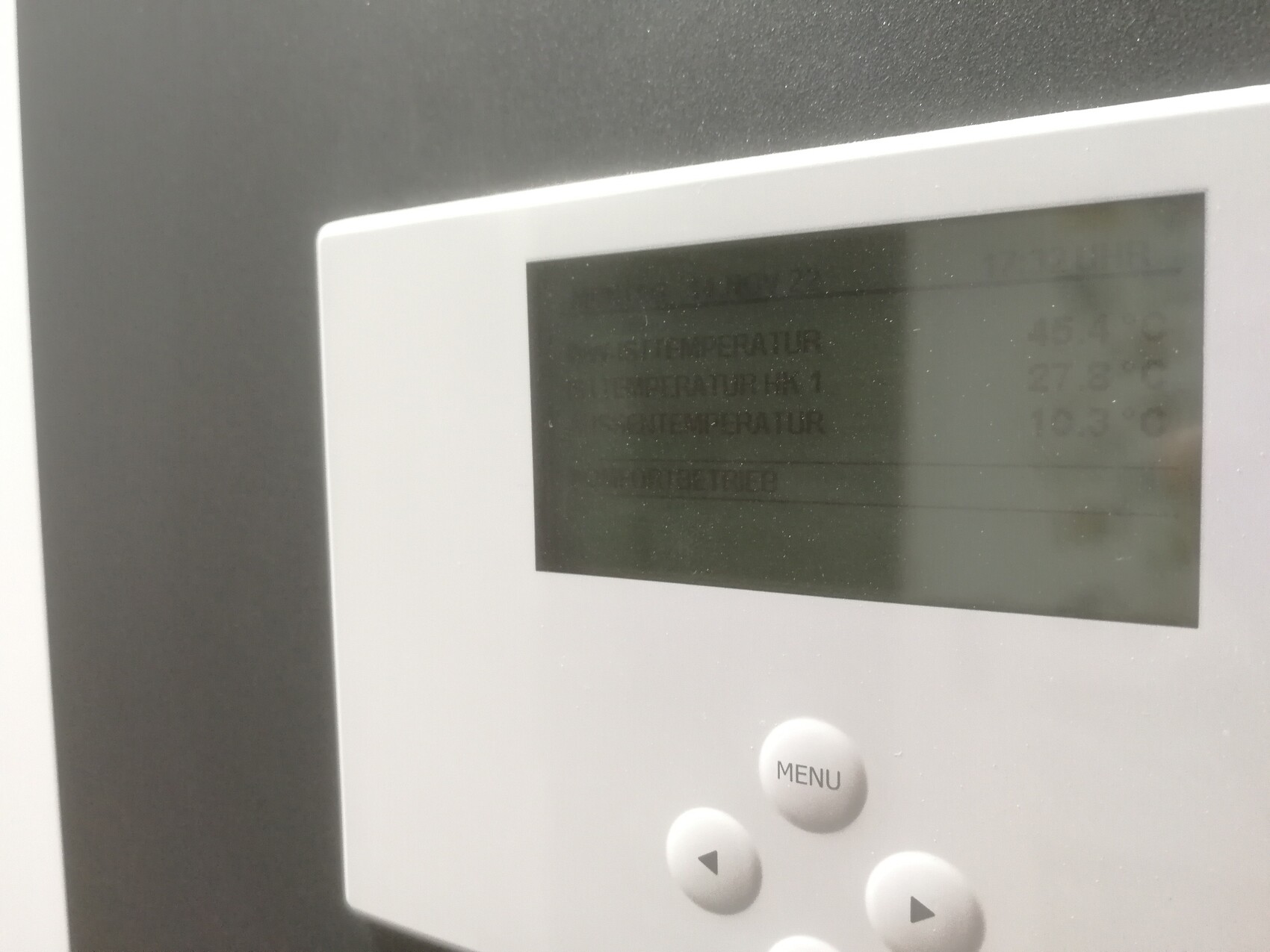 Nahaufnahme eines weißen elektronischen Bedienfelds mit Display und MENÜ-Taste.
