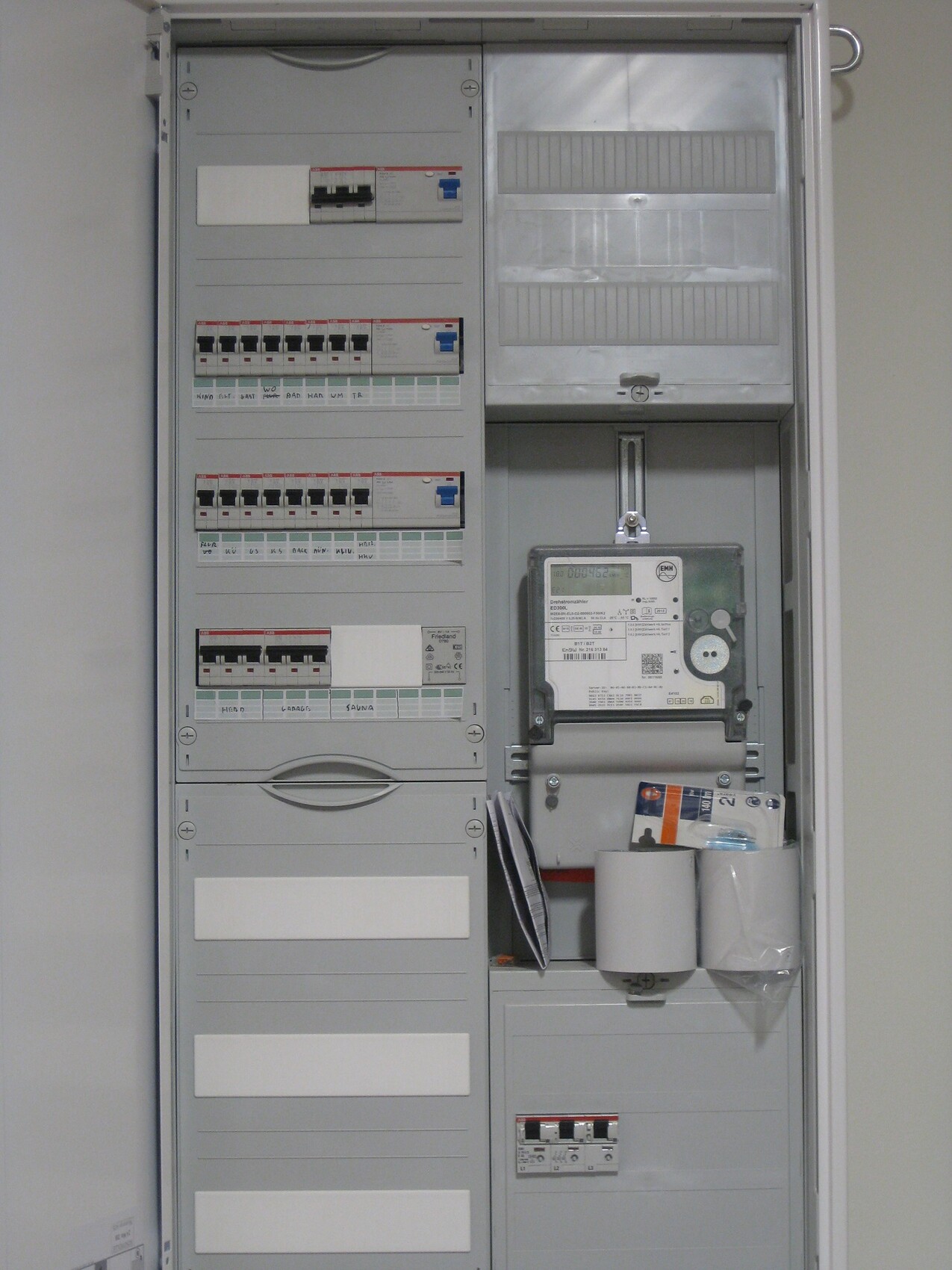 Elektrischer Verteilerschrank mit Zähler, Sicherungen und Kabelmanagement.