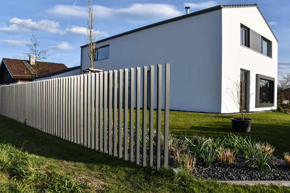 Moderne weiße zweistöckige Villa mit langem vertikalen Lattenzaun im Garten