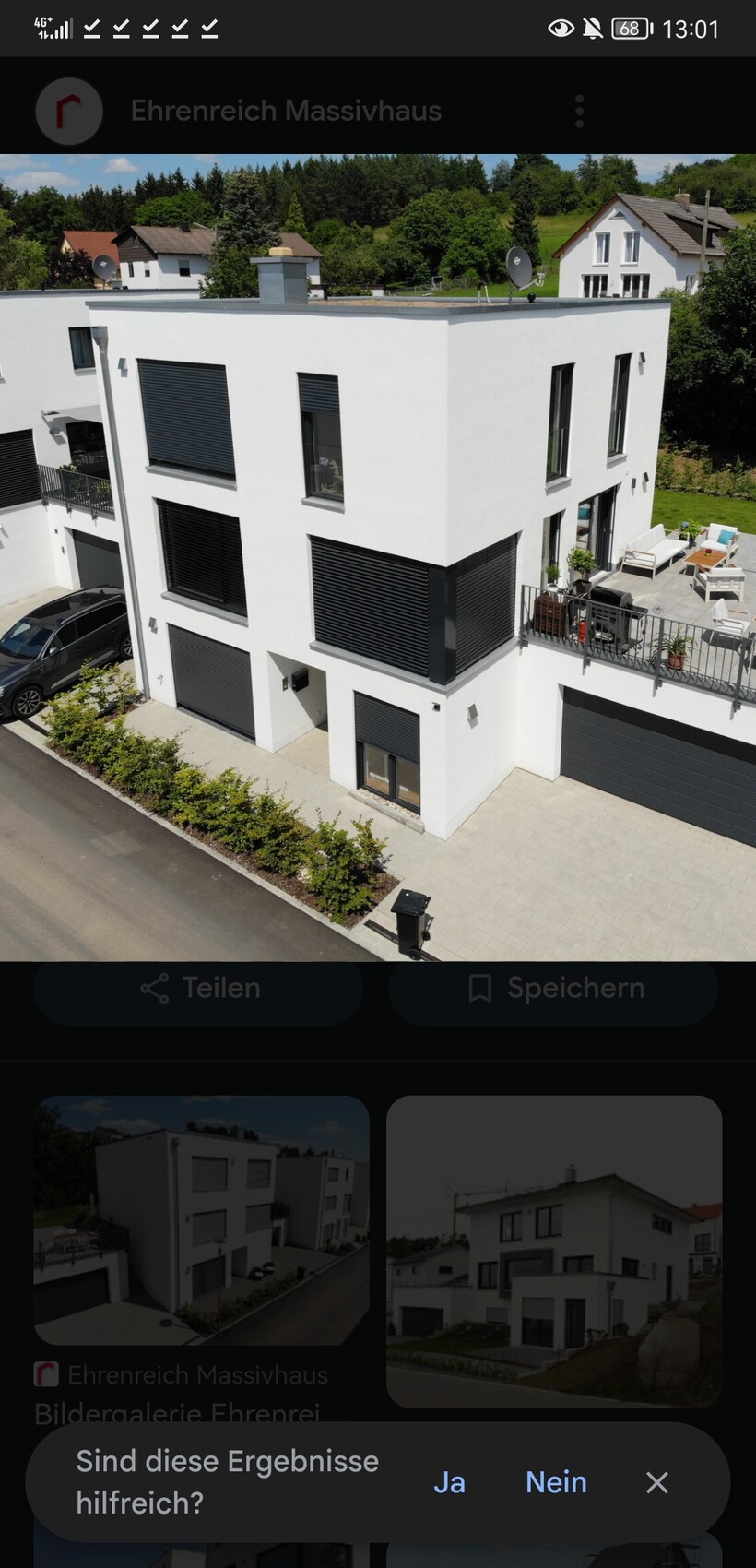 Moderne weisse Kubusvilla mit schwarzen Rolllaeden, Terrasse und Garage
