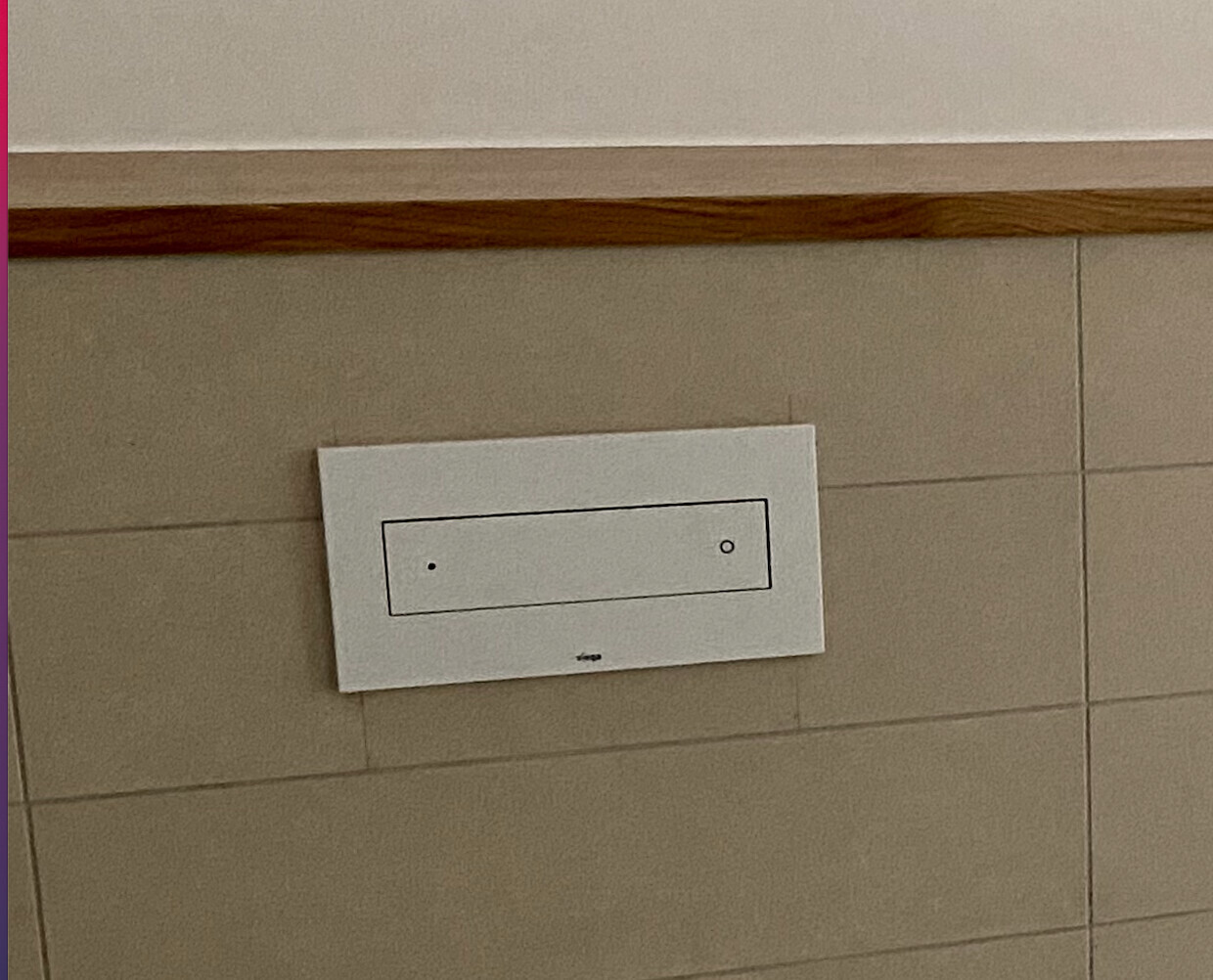 Weißes horizontales Wandpanel mit innerem Rechteck und zwei Kreisen an Fliesenwand.