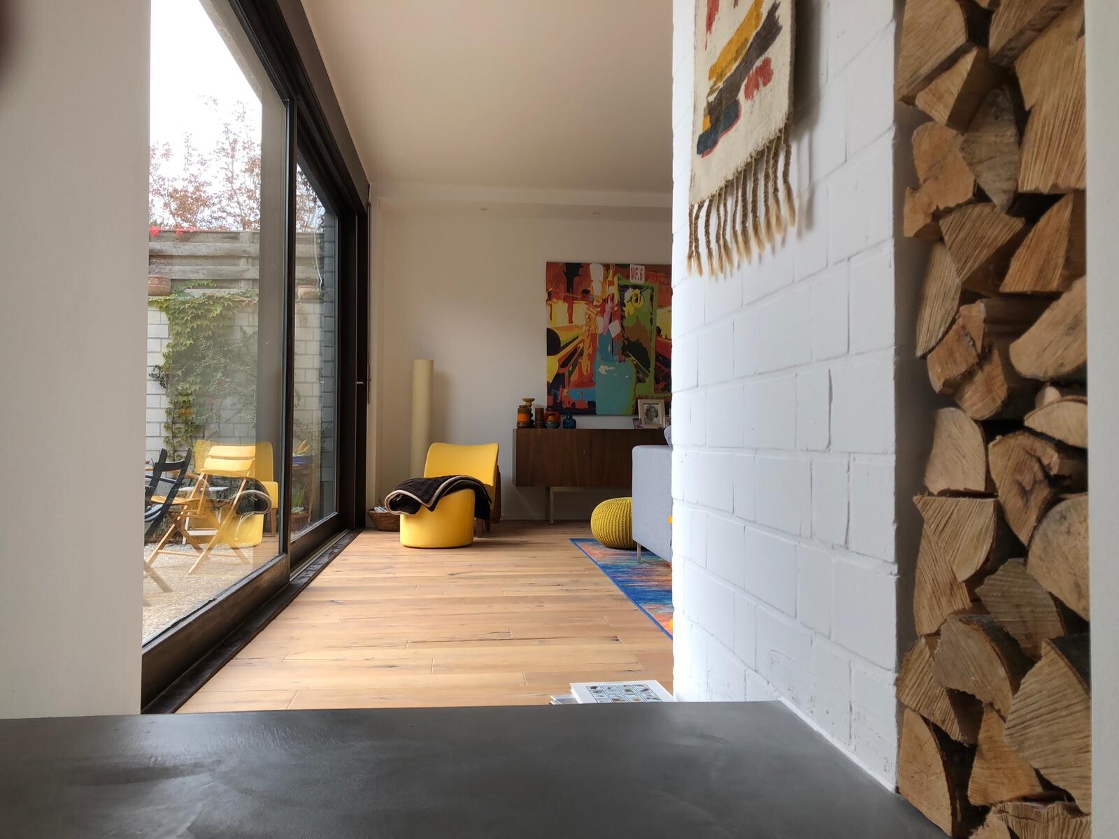 Modernes Wohnzimmer mit Glas-Schiebetüren, Holzboden und gelben Sesseln.