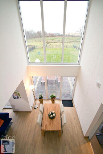 Heller offener Essbereich mit Holztisch, Stühlen und Blumenarrangement; große Fenster zum Garten.