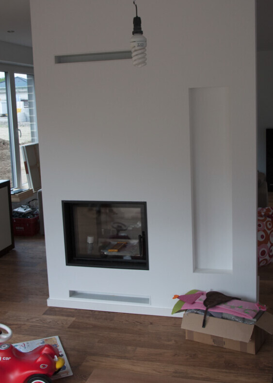 Weiße Wand mit eingebautem Kamin, seitlicher Nische und Spielzeug im Wohnzimmer.
