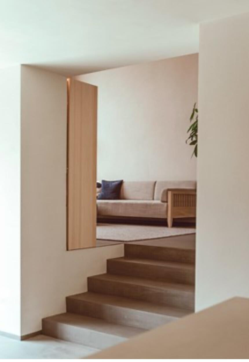 Heller offener Wohnbereich mit Treppenaufgang und Sofa