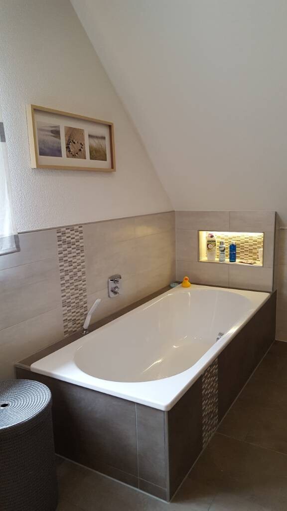 Modernes Badezimmer mit eingelassener Badewanne, Wandfliesen und beleuchteter Nische